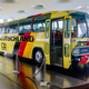 A pale yellow bus with German tricolor stripes on a platform